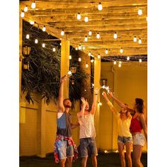 four young people are dancing under an awning with lights strung from the ceiling and around them