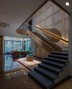 a staircase leading up to a living room next to a glass wall and flooring