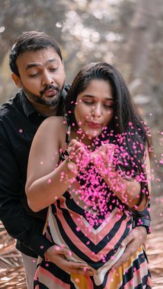 a man and woman standing next to each other with pink confetti in the air