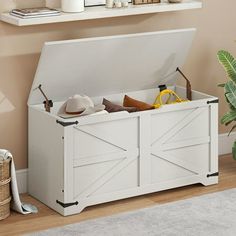 a white storage chest with doors open on the floor next to a rug and potted plant