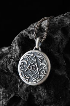 a silver pendant with an eye on it sitting on top of a stone slab in front of a black background