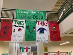 several banners are hanging from the ceiling in a school hallway with holiday decorations on them