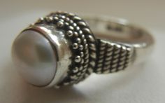 "Bali Suarti sterling silver and pearl ring. Small and beautiful, this ring has a soft iridescent white pearl, set in a raised bezel. The slightly domed pearl is encased in two rows of fine granulation pebbles and two rows of fine braiding. The sides have a striped-pebble vertical design. The back of the setting is solid and the band is thick. Beautifully made in the Balinese tradition and in excellent vintage condition. Please see detailed measurements below. > Size 5.5. *Thank you for doubl Handmade Silver Pearl Ring For Formal Occasions, Unique Sterling Silver Pearl Ring In Silver, Unique Sterling Silver Pearl Ring, Silver Rings With Pearl Drop, Silver Sterling Silver Pearl Ring, Adjustable Vintage Silver Pearl Ring, Vintage Adjustable Silver Pearl Ring, Handmade Silver Pearl Ring, Handmade Vintage Pearl Ring In Sterling Silver