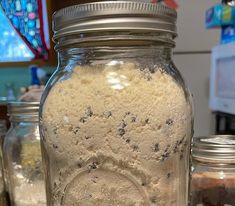 there are many jars with food in them on the counter top and one is filled with powdered sugar