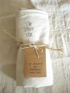 a white cloth wrapped in twine on top of a bed next to a tag that says live laugh love