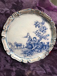 a blue and white plate sitting on top of a purple cloth