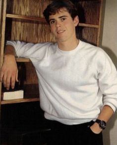 a young man leaning against a book shelf