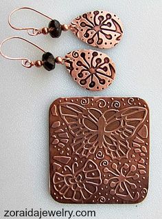 two pieces of copper and black beads are on display next to each other, one is shaped like a butterfly