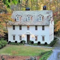 a white house surrounded by trees in the fall