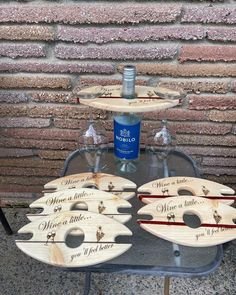 three wine glasses are sitting on a table next to two wooden trays with bottles