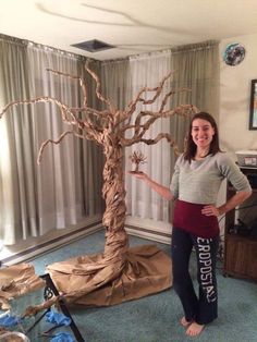 a woman standing next to a fake tree