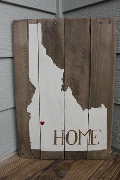 a wooden sign with the word home painted on it and a heart in the middle