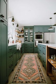 a rug in the middle of a kitchen with green cupboards and drawers on both sides