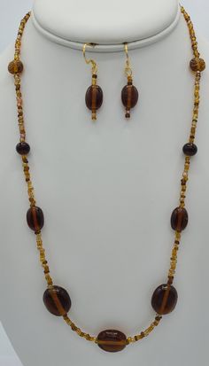 This simple brown beaded necklace was made with brown seed beads and round oblong brown glass beads.  The 22 inch necklace has a 14 K gold plated lobster claw clasp.  The matching earrings are made from the same brown beads as the necklace .  The earrings hang a total of 1 1/2 inches in length and have a 14 K gold plated earring wire. Adjustable Brown Beaded Costume Jewelry Necklace, Adjustable Single Strand Brown Beads, Brown Necklaces With Colorful Oval Beads, Brown Beaded Necklaces With Oval Beads, Brown Czech Glass Beaded Necklaces, Brown Beaded Necklace With Oval Beads, Brown Beaded Necklace With Colorful Oval Beads, Brown Czech Glass Beaded Necklaces With Round Beads, Brown Polished Beads For Jewelry Making