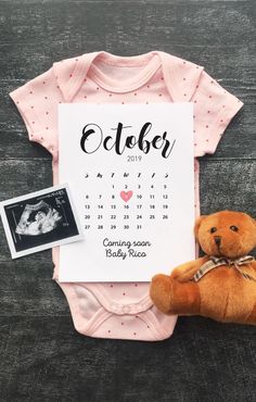 a teddy bear sitting next to a baby's birth announcement on a wooden table