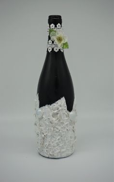 a black bottle with white lace and flowers on it