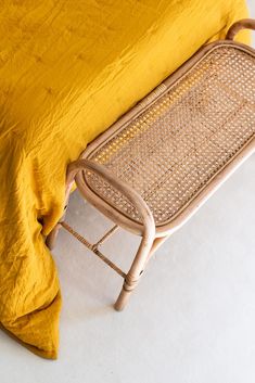 a wicker bed with a yellow blanket on top of it and a white floor