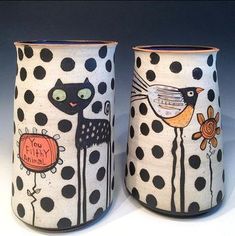 two vases decorated with black and white polka dots, one has a cat and the other has a bird on it