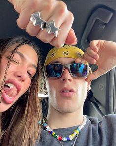 two people in the back seat of a car, one wearing sunglasses and the other with stars on their head