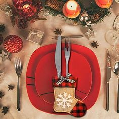 a red plate topped with a christmas stocking next to silverware