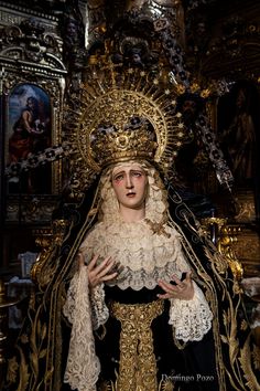 a woman dressed in black and gold standing next to a statue