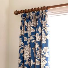 the curtain is hanging in front of the window with blue and white flowers on it