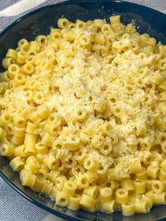 a blue bowl filled with macaroni and cheese on top of a white table cloth