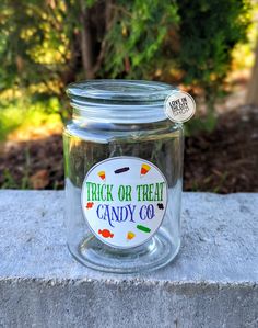 a jar filled with candy sitting on top of a cement block next to some trees