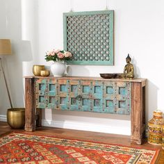 an old wooden table with ornate carvings on it in front of a painting and rug