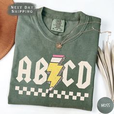 Gear up for the school year with the ABCD Teacher Shirt, crafted from premium Comfort Colors material. Whether you're a Kindergarten or Elementary School teacher, this Back To School Shirt brings both comfort and a fun, educational vibe to your wardrobe. It's also a great Gift for Teachers who love making learning fun. ABOUT US: ✔ Looking for soft, personalized T-shirts that showcase your unique style? Our custom tees are designed for comfort and self-expression! ✔ We are a small, family-owned shop focused on creating high-quality, one-of-a-kind T-shirts and sweatshirts. Each piece is custom-made in our workshop with care and precision.  ✔ Whether it's choosing your favorite color or adding a custom design, we've got everything you need to create the perfect shirt for you. Got any question Green Pre-shrunk Shirt For School, Casual Green T-shirt For School, Green School Spirit Tops For School, Casual Shirt For College End Of School Year, Green Graphic Print School Shirt, Relaxed Fit Shirt For School With School Spirit, Green Graphic Print Shirt For School, Relaxed Fit Shirt With School Spirit, Green T-shirt For School