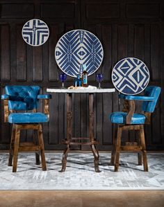 two blue chairs sitting at a table with plates on the wall behind them and an area rug in front of it