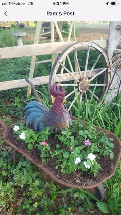 a rooster statue sitting on top of a flower pot in a wheelbarrow filled with flowers