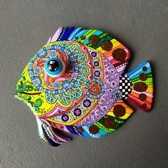 a colorful fish sculpture sitting on top of a wall