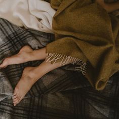 a woman laying on top of a bed under a blanket next to her feet covered in blankets