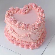 a heart shaped cake with pink frosting and pearls on it's edges, sitting on top of a white card