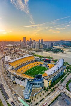 an aerial view of a football stadium with the sun setting in the background and city skyline