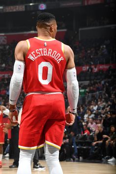 a man in a red uniform standing on a basketball court with his hands behind his back