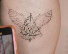 an owl and triangle tattoo on the leg with a cell phone next to it's side