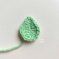 a crocheted green flower on a white surface