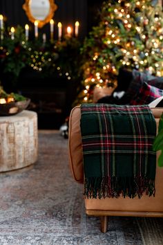 a living room decorated for christmas with lights on the trees in the background and plaid blanket