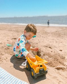 a little boy playing with a toy truck on the beach