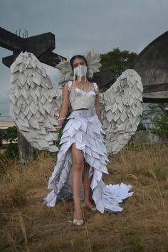 a woman in a white dress with angel wings on her head, standing in a field