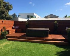 a hot tub sitting on top of a wooden deck next to a lush green field