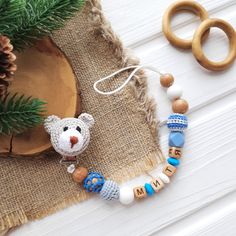 a wooden beaded bracelet with a bear and name on it next to a pine tree