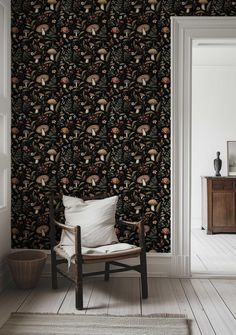 a chair sitting in front of a wallpaper with mushrooms and leaves on it's side