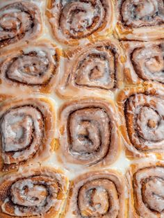 cinnamon rolls with icing sitting on top of a pan