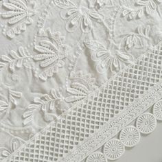 two white lace trims are shown on top of each other, one with an intricate design