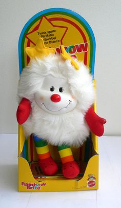 a white stuffed animal in a box with red and yellow striped socks on it's feet