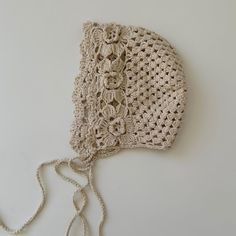 a crocheted hat on a white surface with a string hanging from the side