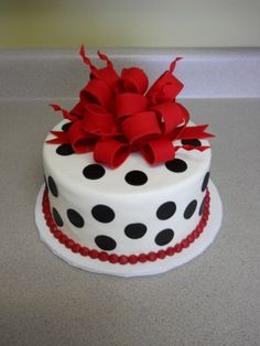 a polka dot cake with red ribbon and bow